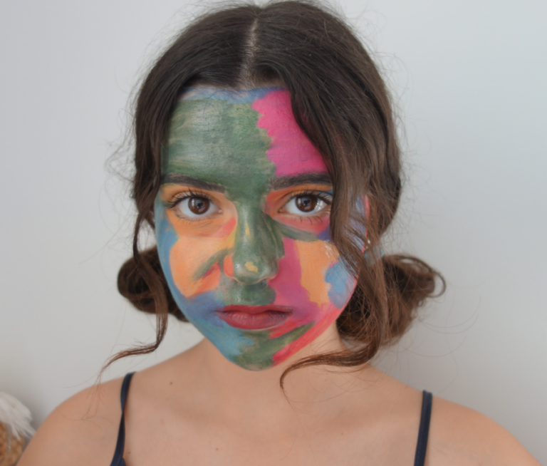 Photograph of the artist with her face painted in overlapping colour fields, used as a colour study