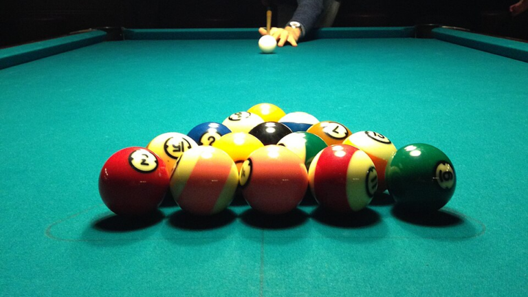 Un triangle complet de billes de billard, prêt à être brisé par la bille blanche
